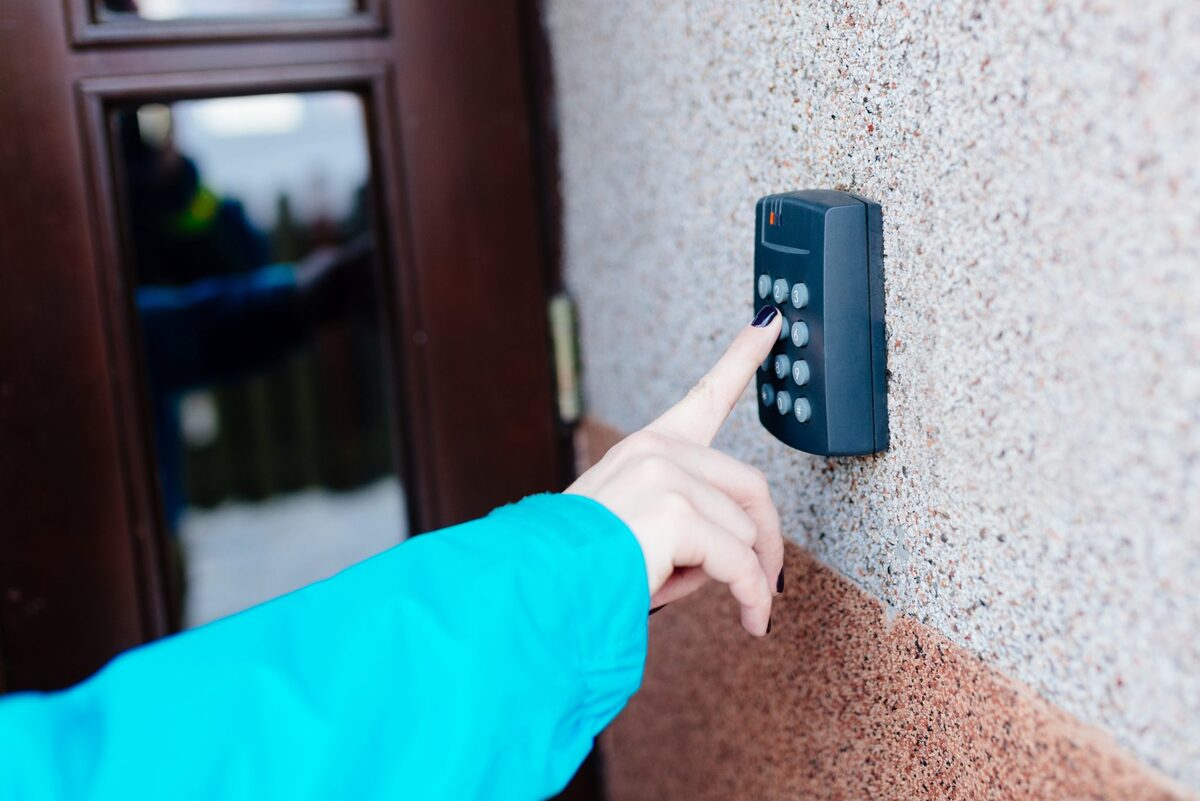Person using a door entry keypad — access control installed by J4 Security Systems