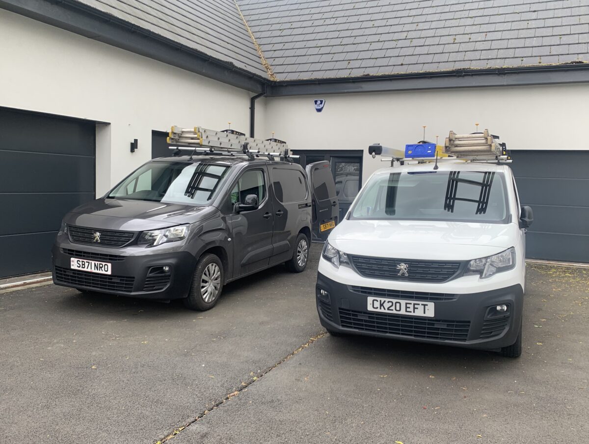 Two J4 Security Systems branded Peugeot vans parked outside a domestic property